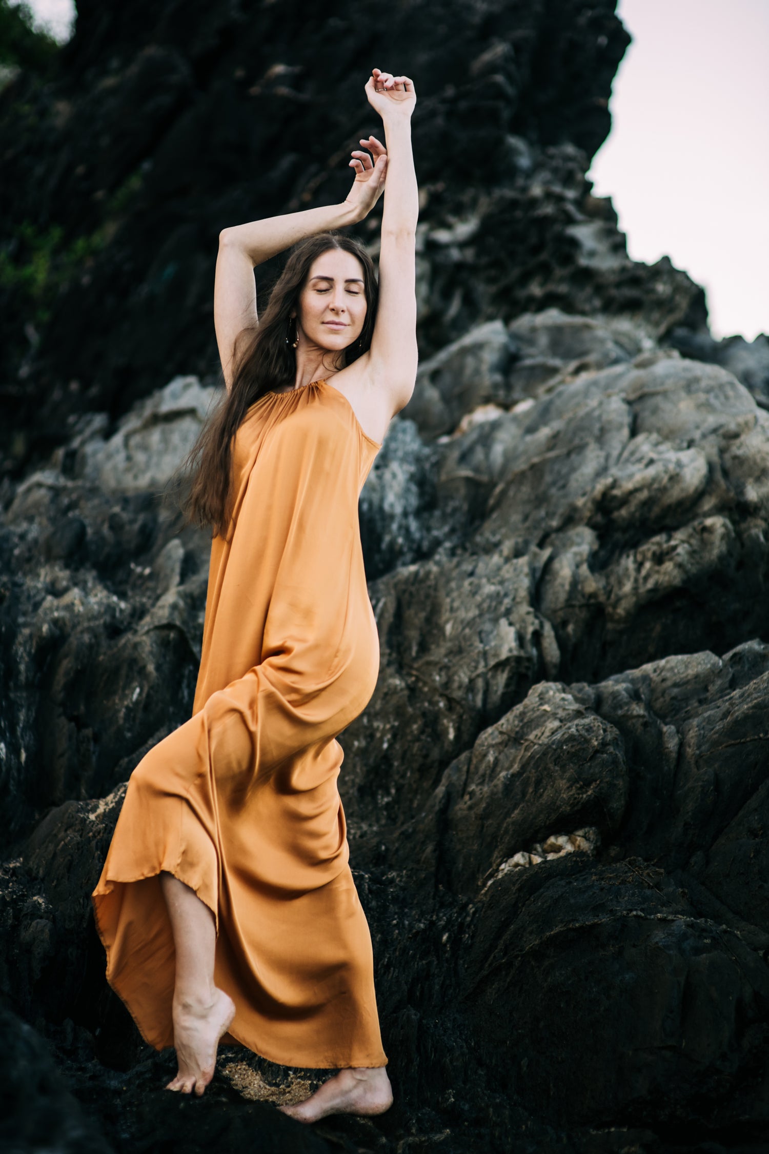Woman in an orange dress standing on rocky terrain