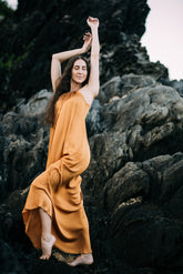 Woman in an orange dress standing on rocky terrain