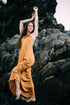 Woman in an orange dress standing on rocky terrain