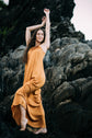 Woman in an orange dress standing on rocky terrain