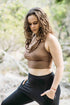 A woman wearing a brown cowl neck tank top and black pants, standing outdoors.