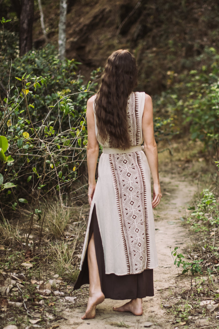 Woman in a patterned dress walking away on a forest path