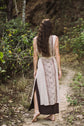 Woman in a patterned dress walking away on a forest path
