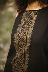 Black garment with gold embroidery on a blurred natural background