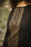 Black garment with gold embroidery on a blurred natural background