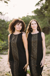 Two women wearing black sleeveless tops with lace details standing outdoors.