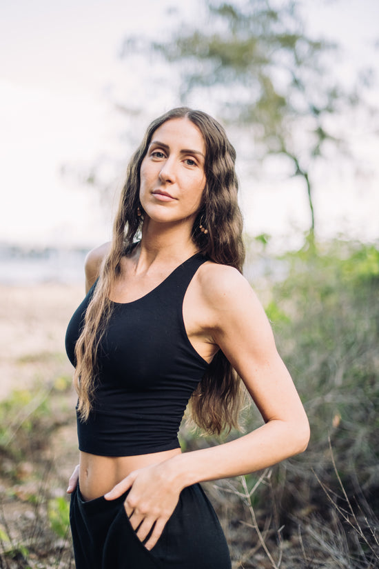 Woman in a black tank top standing outdoors with blurred background